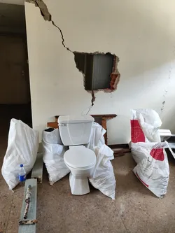 Debris piled up next to another heavily damaged living room wall